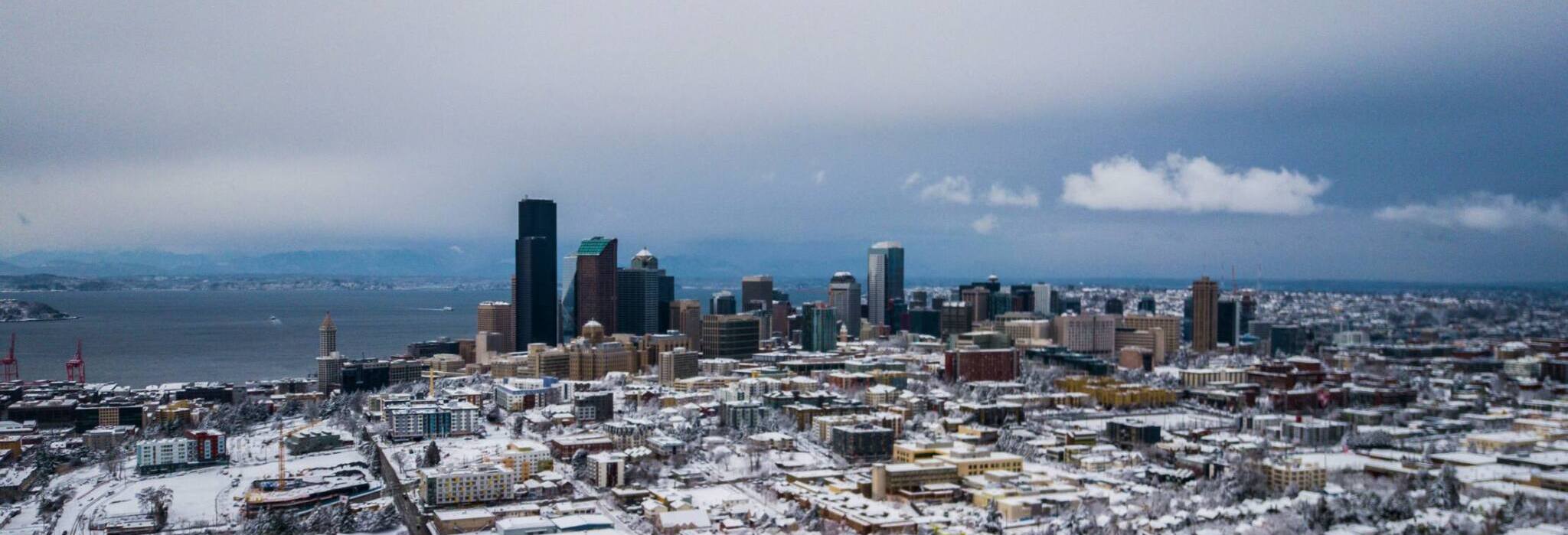 SEATTLE Moving & Storage – Aerial view of downtown Seattle covered in snow with high-rise buildings and waterfront.