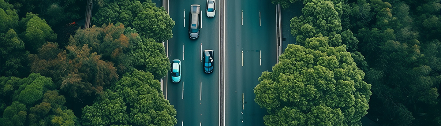 Aerial view of a highway with cars driving through a lush green forest.