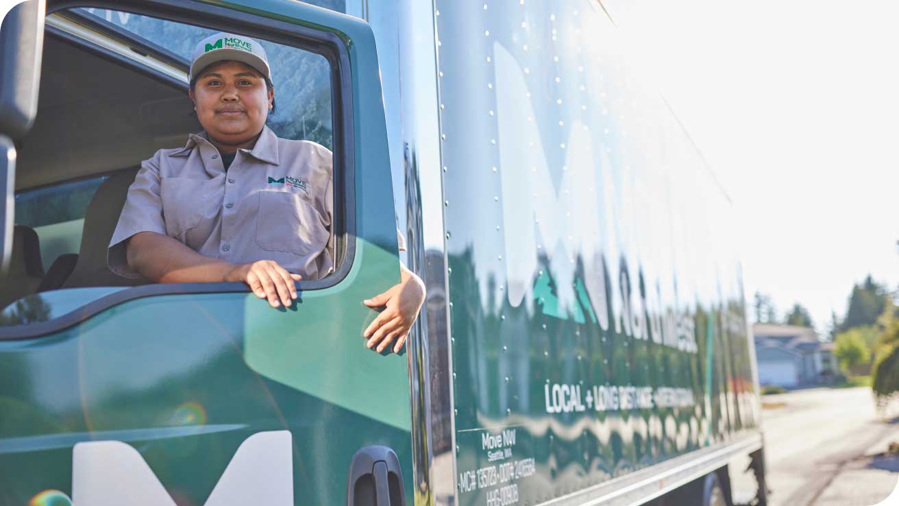 Move Northwest employee smiling from the driver’s seat of a branded Moving Truck.